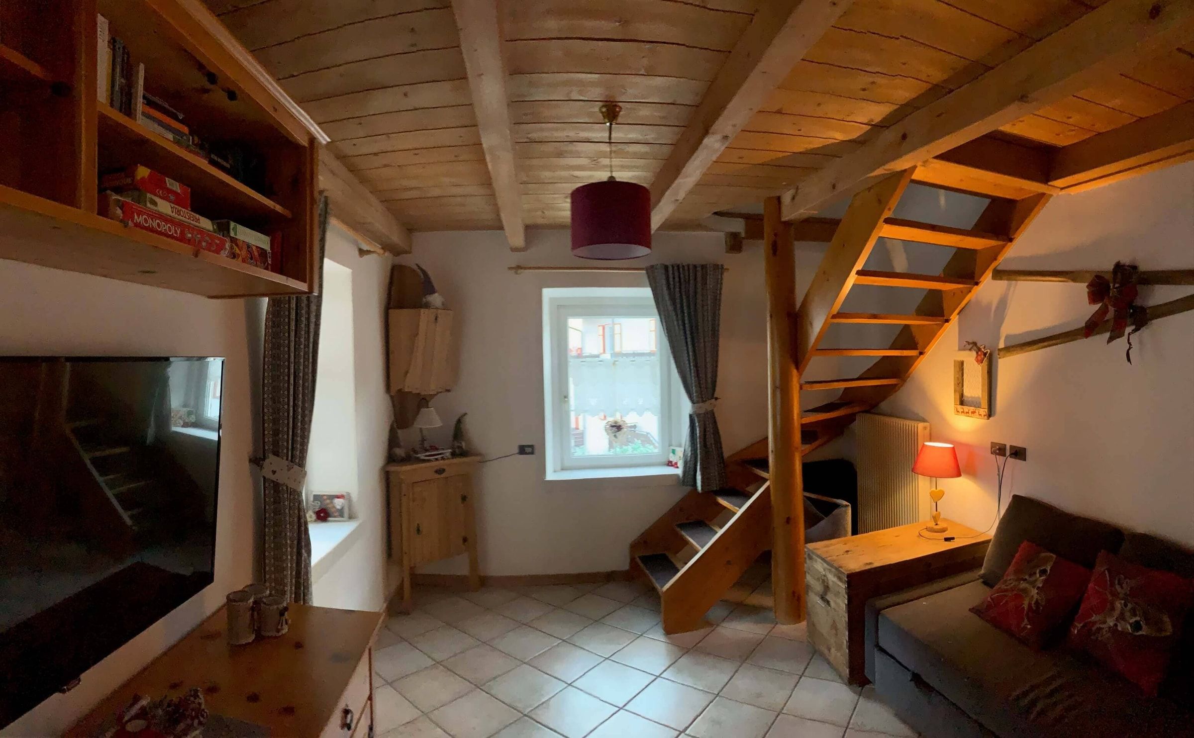 Wohnzimmer mit Sofa, Smart-TV und Holztreppe zum Dachgeschoss