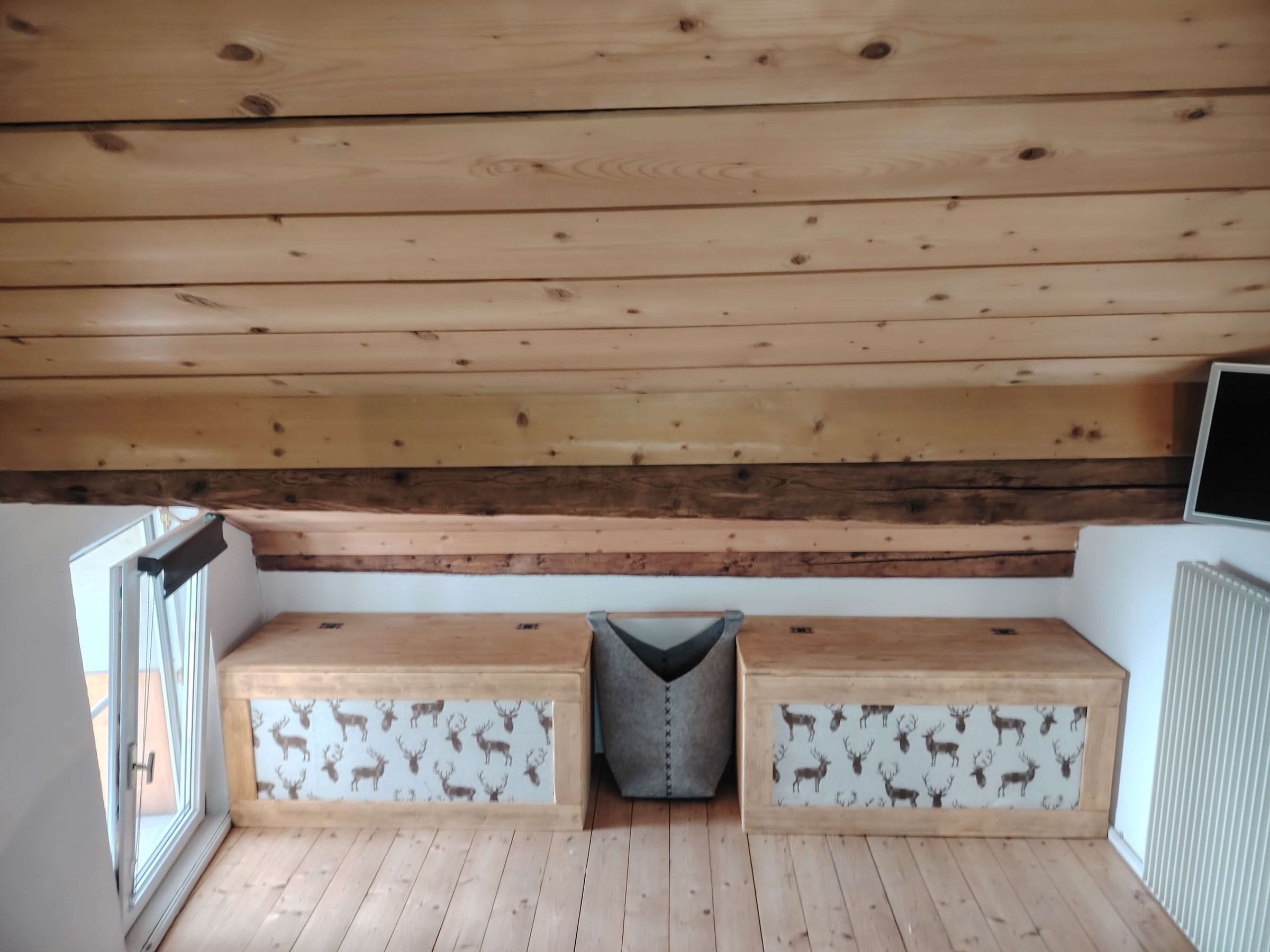 Gemütliche Ecke im Dachgeschoss mit Holzbänken und TV